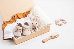 gift basket with gender neutral baby garment accessories care box organic newborn cotton clothes fashion branding small business idea flat lay top view