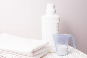 white plastic bottle with bleach laundry detergent measuring cup white plastic basket 286227 1882